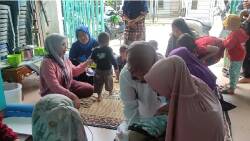 Ketua TP PKK Kelurahan Banuaran Nan XX, Elia Roza membantu kader dan petugas kesehatan saat mengunjungi Pos 8 Yandu Cempaka Putih Banuaran di Rumah Ketua RT 04 RW 11 Kelurahan Banuaran Nan XX,