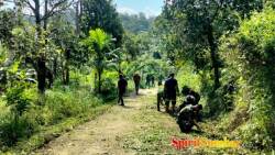 Anggota Satgas bersama dengan masyarakat Desa Bukit Pamewa bergotong royong bersama membersihkan badan jalan